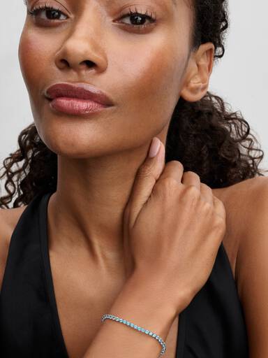 سوار "تنس" مرصّع بأحجار زرقاء فاتحة تتألّق لمعانًا